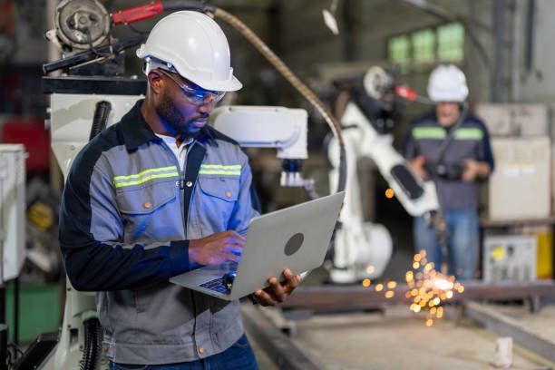 African Mechanical engineer working for maintenance or repairing robotic welding machine in factory. Maintenance and repairing work in modern industry concept.